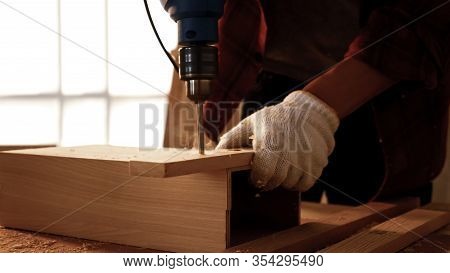 Carpenter Using Drill To Screwing Pieces Of Board At Site.