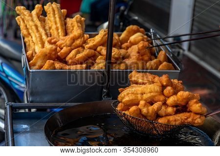 Chinese Deep Fried Dough In Hot Oil On Steel Pan. Youtiao, Padnoongo Or Fried Flour Sticks Is One Of