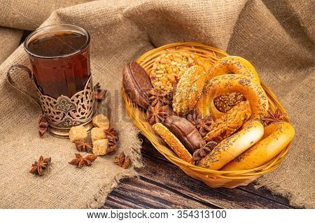 Cookies, Bagels, Chocolate Cakes And Star Anise In A Wicker Basket And A Glass Of Tea In A Vintage C