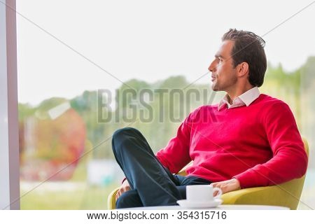 Portrait of thougtful businessman sitting while drinking coffee in lobby