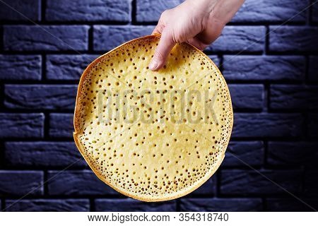 Woman Hand Holds Indonesian Thick Pancake Martabak Manis In Front Of Black Brick Wall