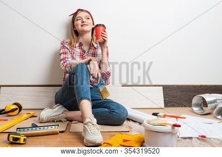 Dreamy Girl Painter Relaxing On Floor With Cup Of Coffee. House Remodeling And Interior Renovation C