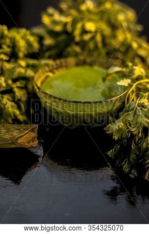 Anti-aging Face Mask On The Black Colored Glossy Surface Consisting Of Fresh Green Cilantro Leaves, 