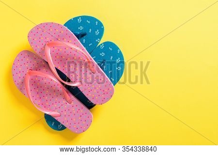 A Lot Of Colored Flip Flops On Yellowbackground. Top View With Copy Space