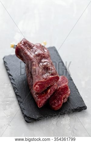 Typical Spanish Smoked Sausage Longaniza On Black Ceramic Board