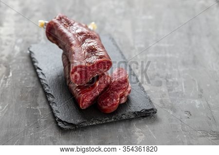 Typical Spanish Smoked Sausage Longaniza On Black Ceramic Board