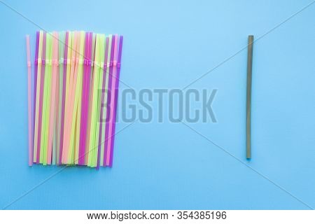 Many Plastic Drinking Straws Vs One Reusable Bamboo Drinking Straw On A Blue Background. Zero Waste 