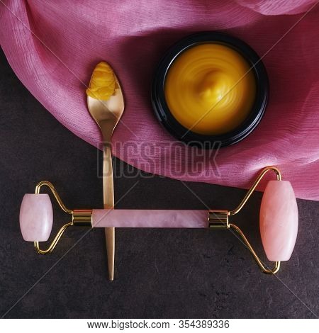 Beautiful Picture Of Golden Solid Skincare Oil In Elegant Black Glass Jar, Golden Spoon And Rose Qua