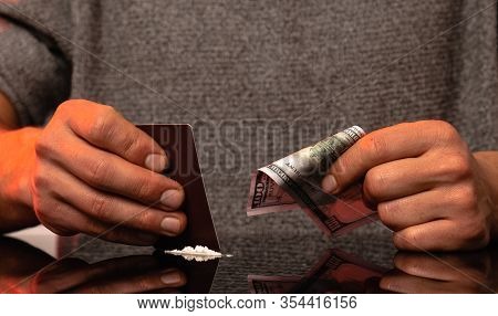 Close-up Of Male Hand Making Lines Of Cocaine Dose With Credit Card And Holds Dollar Banktote In Oth