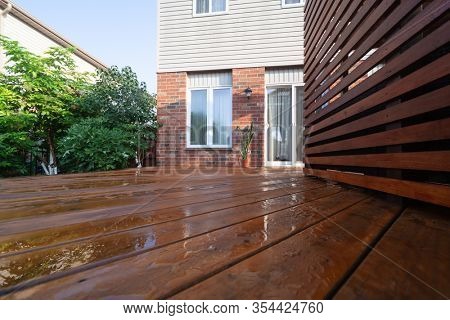 Backyard wooden deck floor boards with fresh brown stain, angled view