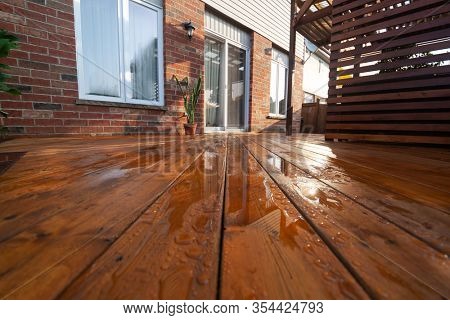Backyard wooden deck floor boards with fresh brown stain, angled view