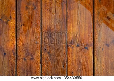 Stained wet deck wooden boards with water drops, brown planks texture