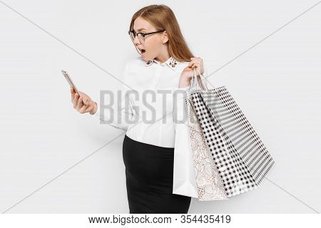 Image Of Young Pregnant Businesswoman Wearing Glasses Holding Smartphone And Bags Shopping