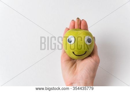 Cute Little Green Apple With Googly Eyes Lying On Palm On White Background.