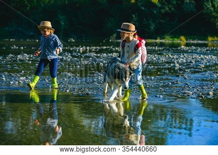 Small Boy And Girl Is Playing With The Dog At The Lake. A Young Couple With Dog Playing Outside On T