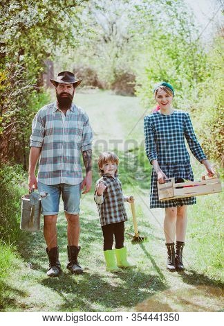 Wife And Husband With Son Planting In The Vegetable Garden. Become Organic Farmers. A Pair With Chil