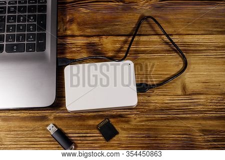 External Hdd Connected To Laptop Computer, Sd Memory Card And Usb Flash Drive On A Wooden Desk. Top 