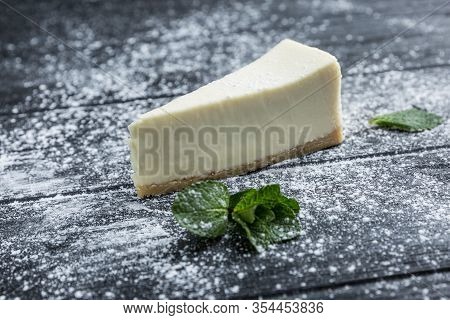 Heesecake With Icing Sugar On The Table Of Their Dark Wood. Close-up.