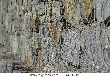 Gabion. Stone Fence In A Metal Mesh. Crushed Stone Packed In Wire Mesh. Granite Texture. Selective F
