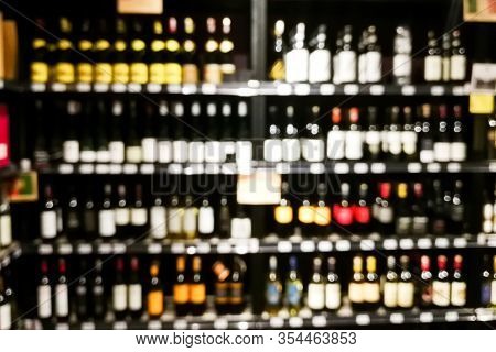 Blurred Wine Section Of Retailer With Bottles On Shelf Display Rack