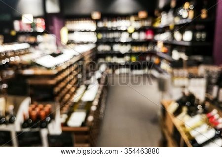 Blurred Wine Section Of Retailer With Bottles On Shelf Display Rack