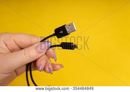 Micro Usb Cable In Hand Close-up On Yellow Background