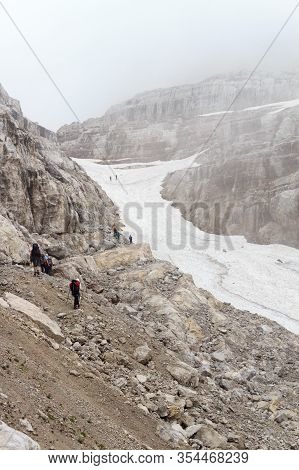 People Hiking Towards Col Bocca Del Tuckett On Snow Field In Brenta Dolomites Mountains, Italy
