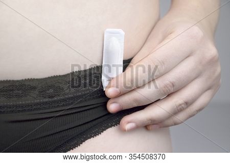Vaginal Or Rectal Candle In The Hands Of A Woman Against The Background Of The Abdomen And Underwear