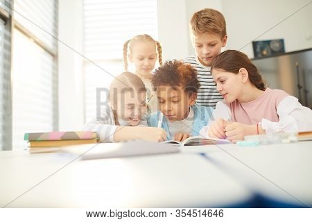 Group Of Good Friends Helping Twelve-year-old Boy With Homework Task He Couldnt Do, Horizontal Shot