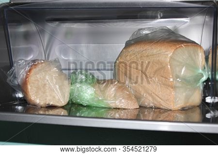 Different Loaves Of Bread In A Bread Box And Cellophane Bags.