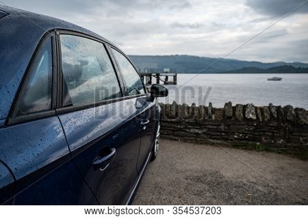 Rear View Of Modern Luxury Dark Blue Car Parked Above The Loch Lomond In Luss With A Romantic View. 
