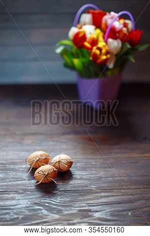 Easter Beige Eggs Decorate With Rope And Bouquet Of Different Color Tulps On Brown Wooden Background