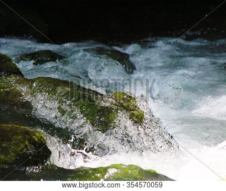 Rushing Water Spilling Over Mossy River Rocks