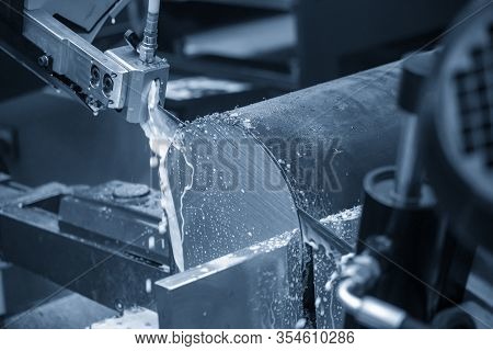 The Operation Of Automatic Band Saw Machine Cutting The Metal Shaft With Liquid Coolant . The Materi