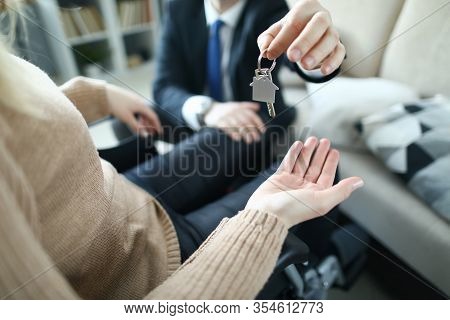 Close-up Of Client And Realtor. Agent Giving Keys Of Apartment To New Owner In Disabled Carriage Aft