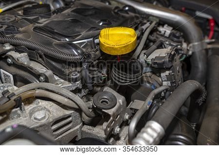 Engine Compartment In Used Car Visible Open Oil Filler In Yellow And Parts Of The Engine.