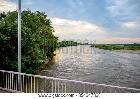 Passing Over The Bridge Over The River. The Landscape Of The River, The Surface And The Trees Of The