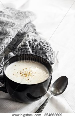 Cauliflower Soup (creme Du Barry) In Black Bowl On White Background With Black And White Cloth. Copy