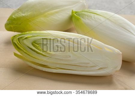 Whole and half fresh raw Belgian endive close up on a cutting board