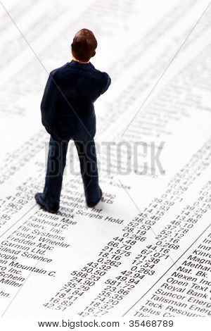 een kleine figuur en de prijzen van aandelen in een krant. geld verdienen op de beurs. winsten en 
