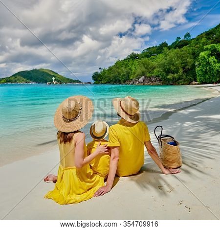 Family on beach, young couple in yellow with three year old boy. Summer vacation at Seychelles. Port Launay, Mahe. 