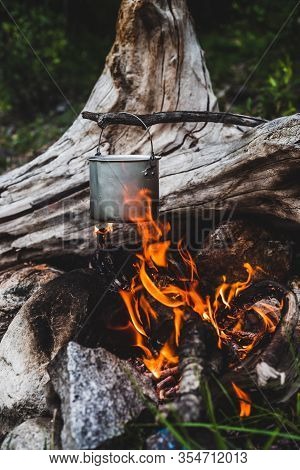 Kettle Hanging Over Fire. Cooking Food At Fire In Wild. Beautiful Big Log Burns In Bonfire Close-up.