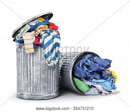 Heaps Of Clothes In Iron Dumpsters Isolated On A White Background. Consumption Concept.