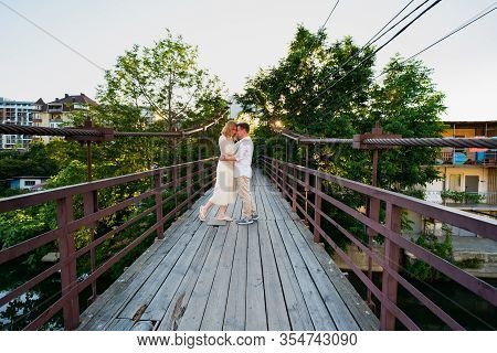 A Couple A Man And A Woman In White On A Wooden Bridge Over The Dagomys River In The Summer In Sochi