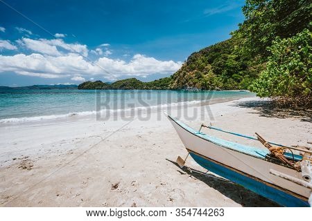 Traditional Banca Boat In Front Of Remote Tropical Beach With Exotic Blue Lagoon. El Nido, Philippin