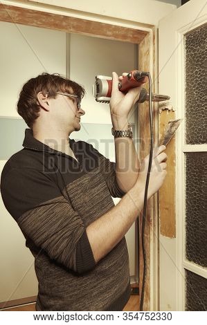 Man At Home Removing Havy Layer Of Old Paint From Door