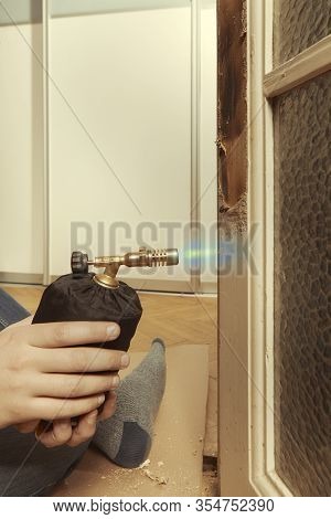 Man At Home Removing Havy Layer Of Old Paint From Door With Burner