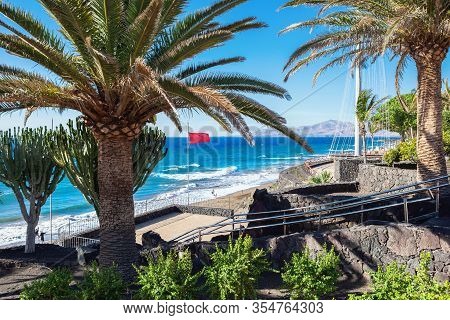 Stone Path In Puerto Del Carmen Beach In Lanzarote, Canary Islands, Spain. Blue Sea, Palm Trees, Sel