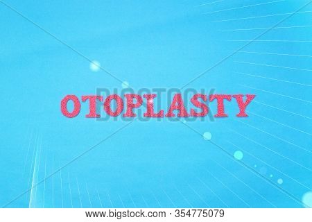Word Otoplasty In Red Letters On A Blue Background. The Concept Of Plastic Surgery To Change The Sha