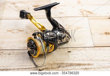 Golden Fishing Reel On Wooden Floor, Equipment With Pe Line, Rust-proof Technology, Ball Bearing Sys